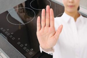 piano ad induzione e donna con mano che fa segno stop