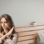 testiera letto in legno e donna che fa stop con le mai