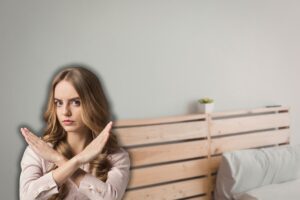 testiera letto in legno e donna che fa stop con le mai
