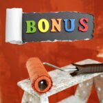 Un rullo per tinteggiare colorato di rosso ed un muro sullo sfondo tinteggaito di rosso e con sopra una scritta "bonus"