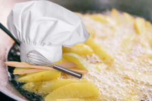 patatine che friggono in olio e cappello da chef