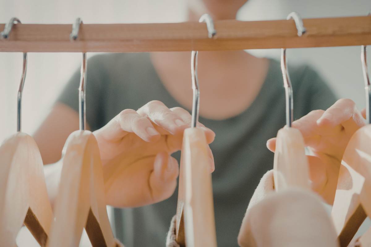 donna che sistema armadio con delle stampelle appese