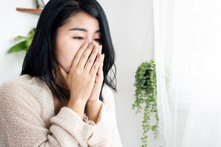 Una ragazza che si tappa bocca e naso per via del fumo in casa