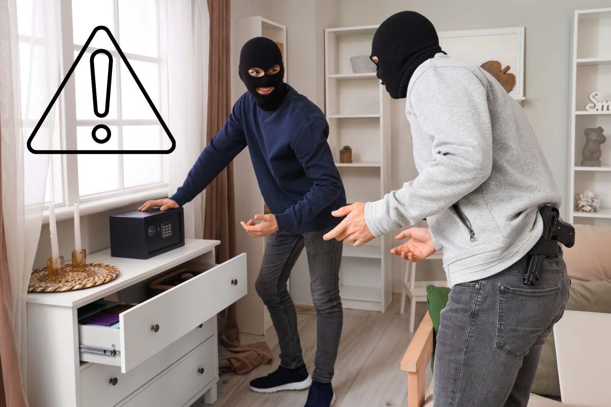 Dei ladri che stanno derubando una casa ed un segnale di pericolo in alto a sinistra