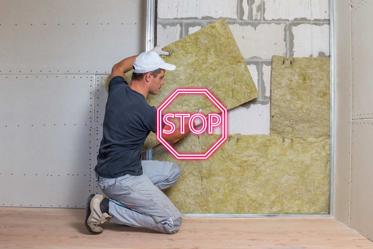 Un uomo che impianta dei pannelli di lana di vetro ed un segnale di stop in primo piano