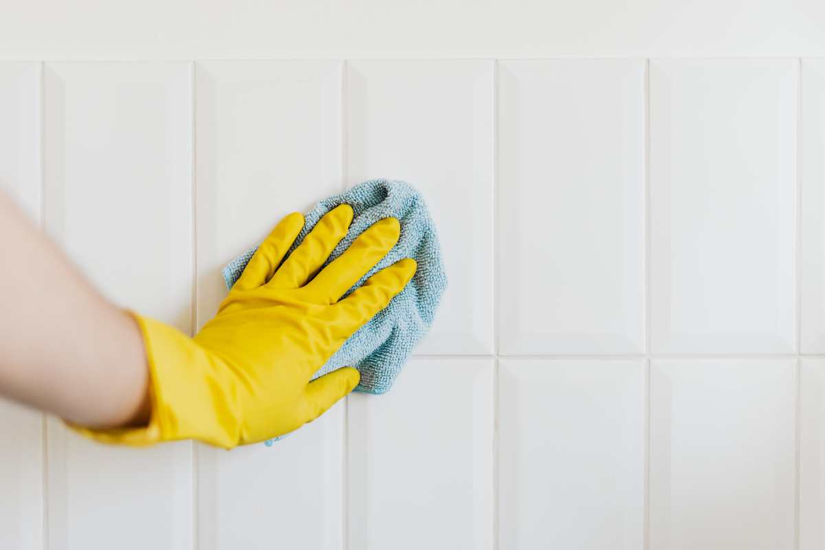 mano che pulisce su mattonelle 