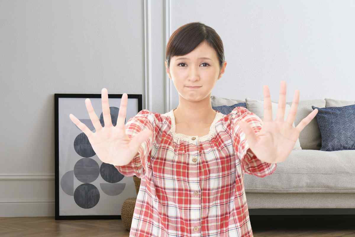 donna che fa segno con le mani di fermarsi e salotto nello sfondo