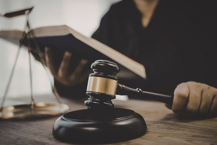 Un giudice con il suo martello che lo sbatte e ha un libro di legge in mano