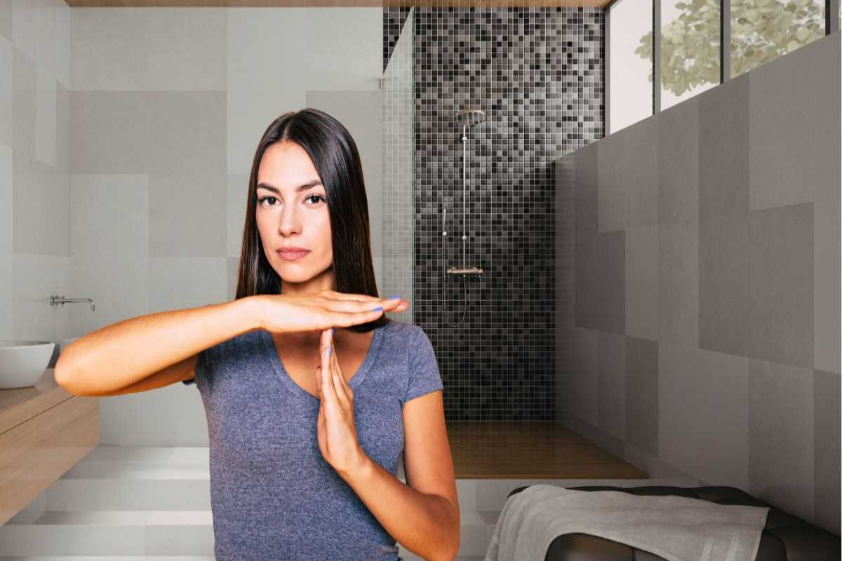 sfondo in cui si vede un bagno moderno con una doccia walk in e in primo piano una donna che dice no con le mani